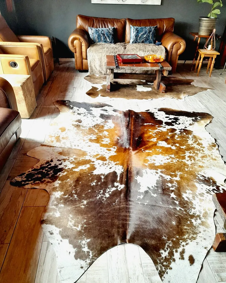 Tri-colour speckled Nguni hides in a lounge with leather sofas